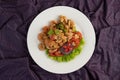 Stir shrimp macaroni on a white plate with tomatoes and salad