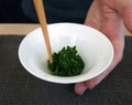 Stiring fresh green tea leaves in white cup with chopsticks