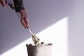 Stirrer in the hand of a worker in a cement mortar and an old rusty bucket close up