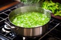 stirring bright green pea soup in a pot on the stove