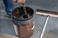 Stirring can of asphalt before pouring on driveway