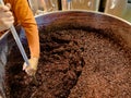 Stirring and mixing barrique pinot noir grapes fermenting in an open tank during wine-making