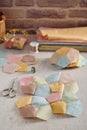 Stitched quilting blocks, piles of blocks and pentagons, stacks of fabrics, sewing accessories