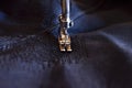 Stitching, stitch a hole in dark jeans or knit sweatpants with a sewing machine. Part of the sewing machine and denim closeup Royalty Free Stock Photo