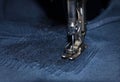 Stitching, stitch a hole in dark jeans or knit sweatpants with a sewing machine. Part of the sewing machine and denim closeup Royalty Free Stock Photo