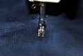 Stitching, stitch a hole in dark jeans or knit sweatpants with a sewing machine. Part of the sewing machine and denim closeup Royalty Free Stock Photo