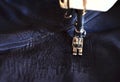 Stitching, stitch a hole in dark jeans or knit sweatpants with a sewing machine. Part of the sewing machine and denim closeup Royalty Free Stock Photo