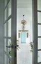 Stylish and light hall interior design with white walls and floor, blue doors, plants and pictures.