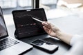 Stock investor holding a pen pointing a tablet screen that opens a stock chart program to read stock price charts. Royalty Free Stock Photo