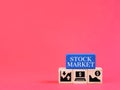 Stock market phrase on wooden blocks with symbols against red background and copy space. Royalty Free Stock Photo