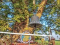 Stock photo of ancient copper or bronze bell hanging on a iron frame at Hindu temple, green tree on background. Picture captured Royalty Free Stock Photo