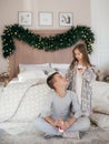 Eautiful little girl and boy are on the bed in the bedroom with Christmas decoration