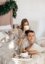 Eautiful little girl and boy are on the bed in the bedroom with Christmas decoration