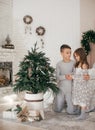 Eautiful little girl and boy are on the bed in the bedroom with Christmas decoration