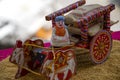 Stock photo of a beautiful traditional Indian wooden bull cart and statue of farmer sitting on bull cart, kept on grains on sunny