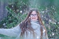 Blonde girl with glasses smiles looking at the camera. Photo in the snowing forest, warm girl in a gray pullover