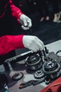 Mechanic wearing white gloves building engine picking up a gear from working table Royalty Free Stock Photo