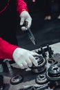 Mechanic wearing white gloves building engine picking up a gear from working table Royalty Free Stock Photo