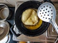 Stock photo of deep fried puri, women frying wheat flour puri or bhatura until its get golden brown color in cooking oil.