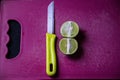 Stock photo of fresh juicy cut lemon kept on purple color chopping board with yellow color knife, focus on object. blur background Royalty Free Stock Photo