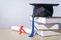 Stock photo of a graduation cap mortar board with books and diploma certificate isolated on wooden table against white background Royalty Free Stock Photo