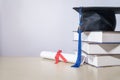 Stock photo of a graduation cap mortar board with books and diploma certificate isolated on wooden table against white background Royalty Free Stock Photo