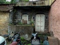 Stock photo of old damaged broken abandoned house, old rusty scooter and other vehicles parked in front of house. The front wall Royalty Free Stock Photo