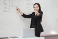 Stock photo portrait of a confident cheerful Asian woman teacher in a black business suit uniform with a digital tablet and laptop Royalty Free Stock Photo