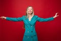 Smiling cheerful blonde woman in blue dress with outstretched dress.