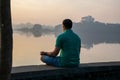 Stock photo of 30 to 40 year old Indian man practicing pranayama or yoga or meditation by the lake sitting in lotus pose at Royalty Free Stock Photo