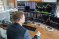 Stock trader looking at computer screens in trdading office.