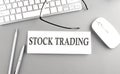 STOCK TRADING text on paper with keyboard on grey background