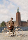 Man wearing old fashioned tweed suit and hat holding a retro bicycle in front of Stockholm City Hall Royalty Free Stock Photo