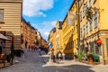Stockholm, Sweden - July, 2018: The narrow cobblestone cozy street with yellow medieval houses of Gamla Stan historic old center