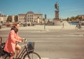 Woman riding bicycle past historical bronze statue of Gustav III, swedish King from 1771