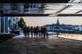 Stockholm, Sweden - Mixed group of young people walking under a bridge along the river towards the sea at dusk Royalty Free Stock Photo