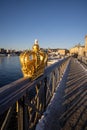 Stockholm in winter. People walking on the bridge with a gilded crown on Skeppsholmsbron