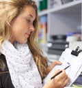 Stocking up on the right requirements. Cropped image of a pretty young woman in a shop making notes on a list. Royalty Free Stock Photo
