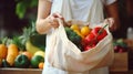 stockphoto, Female hands puts fruits and vegetables in cotton produce bag at food market. Reusable eco bag for shopping.