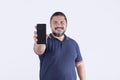 A stocky, beared man of mixed race and in his 30s shows his cellphone.  on a white backdrop. Communications concept Royalty Free Stock Photo