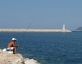 A stoked fisherman catches fish from the pier in front of the lighthouse. Royalty Free Stock Photo