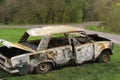 Stolen and abandoned vehicle. Criminals stole and threw the car in Park. Burnt car in the woods on the grass Royalty Free Stock Photo