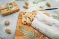 Stollen cake on wooden board, cutlery and gift on gray. Christmas composition