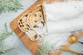 Stollen cake on wooden board, cutlery and gift on gray. Christmas food composition