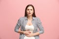 The stomach ache. The sad woman with stomach ache or pain on a pink studio background.