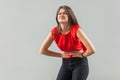 Stomach, belly pain. Portrait of sick sad brunette young woman in red shirt standing and holding her painful problem belly Royalty Free Stock Photo