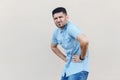 Stomach pain or diet problem. Portrait of sick handsome young bearded man in blue shirt standing and holding his painful belly, Royalty Free Stock Photo