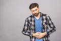Stomach pain or diet problem. Portrait of sick handsome young bearded man in casual standing and holding his painful belly, Royalty Free Stock Photo