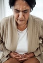 Stomach pain, sick or illness with a senior woman in her home, holding her belly in discomfort. Healthcare, medical and Royalty Free Stock Photo