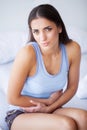 Stomach Pain. Unhealthy young woman with stomachache leaning on the bed at home Royalty Free Stock Photo